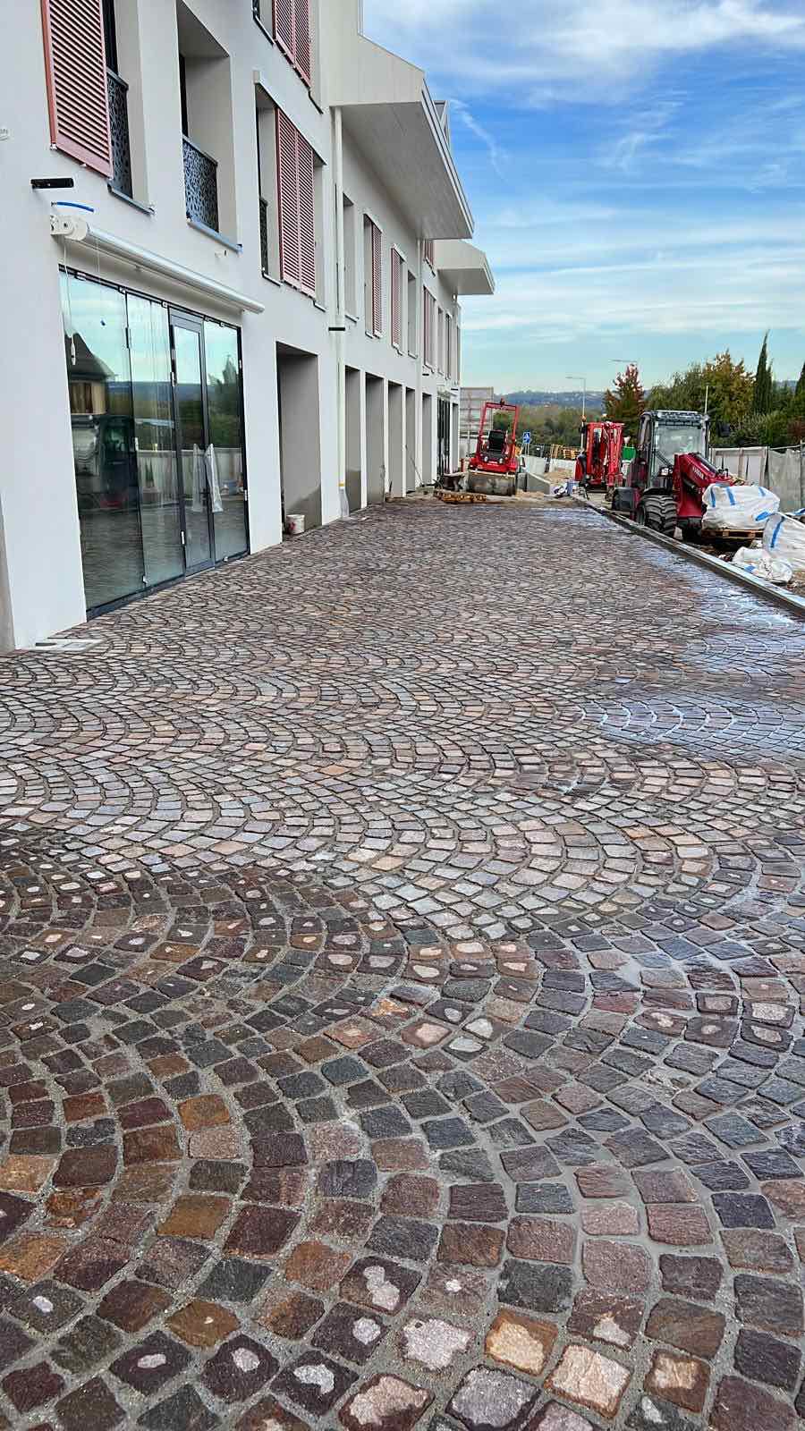 Grande cour résidentielle en pavés avec pose cintrée devant une maison