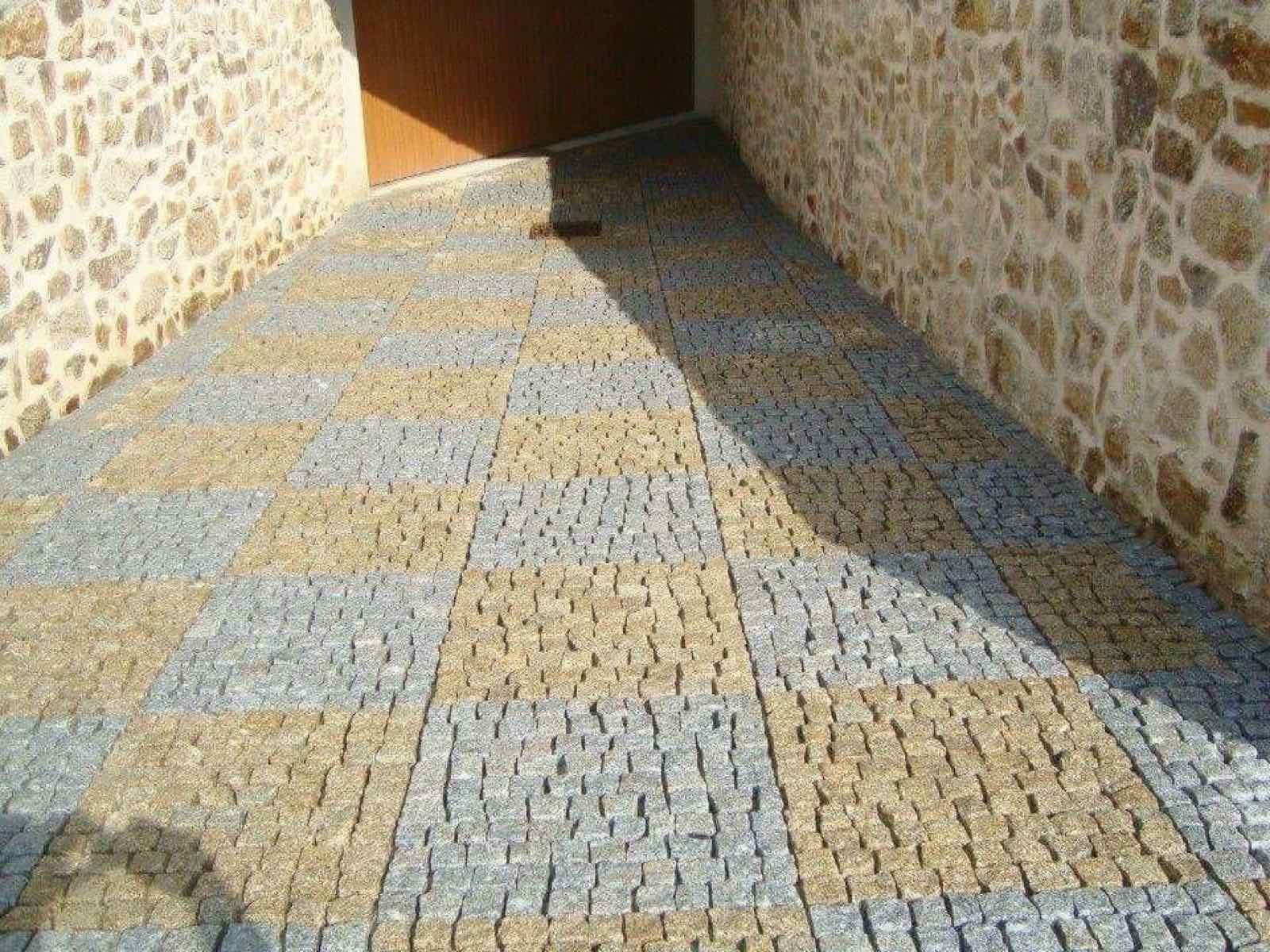 Passage pavé aux teintes naturelles entre deux murs en pierre